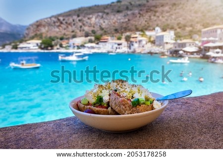 A traditional Greek salad with Manouri Cheese from the Mani region in Greece in front of turquoise sea