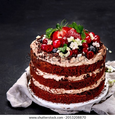 Delicious homemade chocolate cake with fresh berries and mascarpone cream on dark background. 