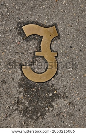 Worn brass pound sign in wet stone or asphalt on the road. Selective focus
