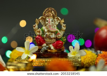 Statue Of Ganpati Bappa Morya Hindu God Ganesha Sitting On Golden Asana With Fruits, Flowers, Lamp, shunkh And Blur Bokeh For Diwali Puja New Year Deepawali Ganesh Chaturthi Or Shubh Deepavali Pooja Royalty-Free Stock Photo #2053218545