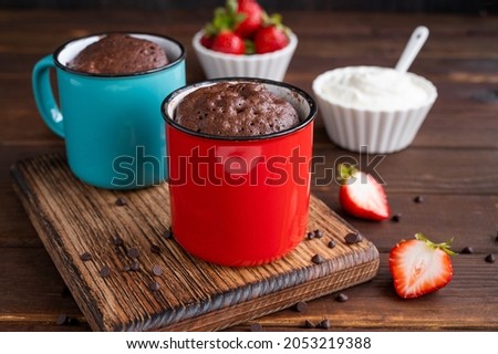 Chocolate mug cake with whipped cream and fresh berries on a dark wooden background. Cupcake cooked in the microwave Royalty-Free Stock Photo #2053219388