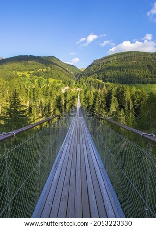 Vanishing point of long wooden suspension bridge in swiss alps. The border between two regions separated for a river. Royalty-Free Stock Photo #2053223330
