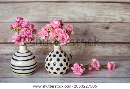 Beautiful Pink Roses in Small Vases with Dots on a Wooden Background  .Home Decoration Elements 