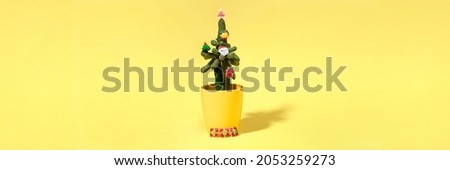 Cactus decorated with Xmas symbols as alternative Xmas tree on yellow with copy space. Banner.