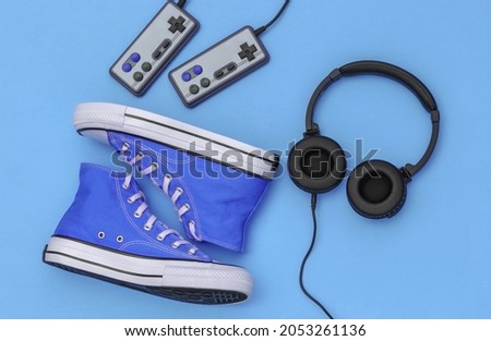 Sneakers, headphones and joysticks. Flat lay composition of retro youth accessories 80s on blue background. Top view