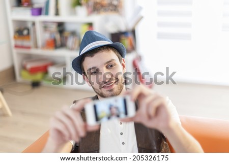 young man is taking a selfie with a smartphone