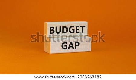 Budget gap symbol. Wooden blocks with words 'Budget gap'. Beautiful orange background. Business and budget gap concept. Copy space.