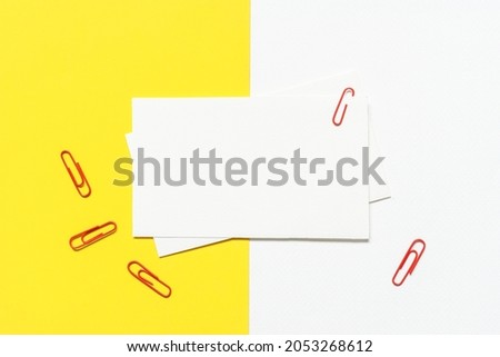 blank white paper with red paper clips on yellow  and white paper background.