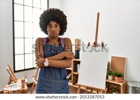 Young african american woman with afro hair at art studio shaking and freezing for winter cold with sad and shock expression on face 