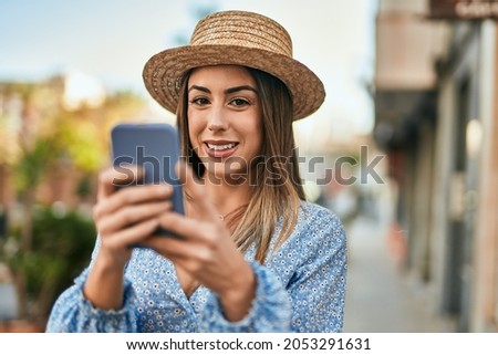 Young hispanic woman smiling happy using smartphone at the city