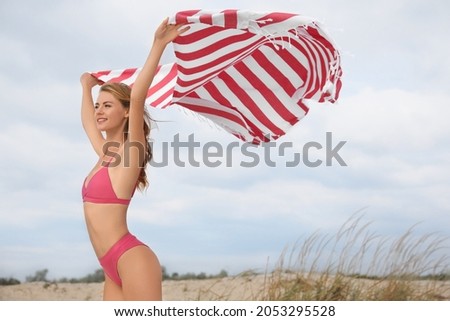 Beautiful woman in bikini with beach towel on sand