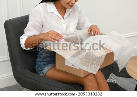 Happy young woman with parcel at home, closeup. Internet shopping