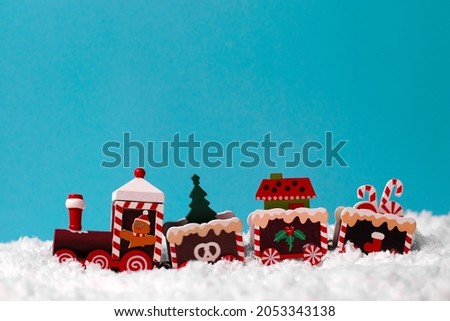Toy wooden train on white snow on a blue background. Copy Space. Children's useful educational toys under the Christmas tree. Picture for a website or poster for a toy store.