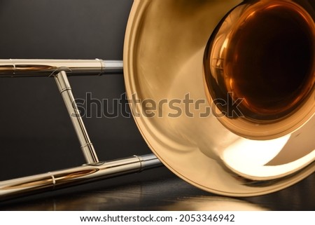 Trombone bell and slide detail on table and black background. Front view. Horizontal composition. Royalty-Free Stock Photo #2053346942