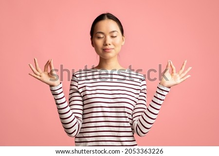 Zen. Relaxed Peaceful Asian Woman Meditating With Closed Eyes, Calm Young Korean Female Practicing Yoga, Keeping Hands In Mudra Gesture, Standing Isolated Over Pink Background, Copy Space