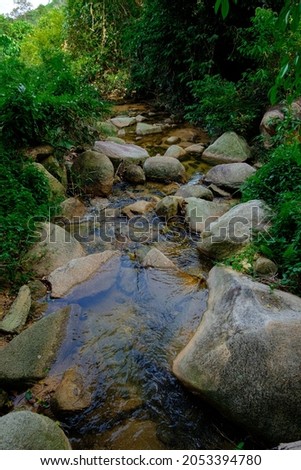 View of a stream with rocks in the jungle at Asahan, Melaka, Malaysia.