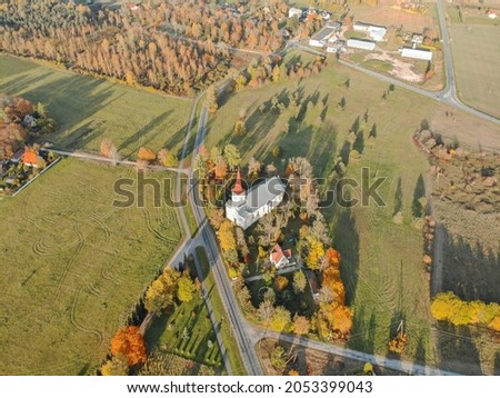Drone photo of small village named Raasiku. Main road and the church next to it. Autumn vibes,colors and nice sunshine. Aerial view of autumn nature in Estonia. Colorful autumn view of small village