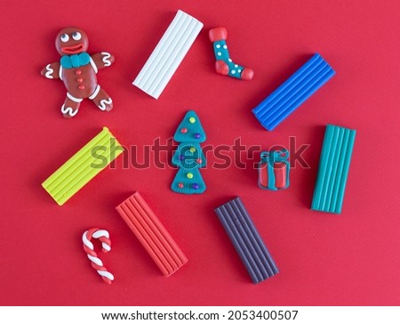 plasticine homemade figures, symbols of the new year and Christmas pieces of plasticine on a red background. Flatlay
