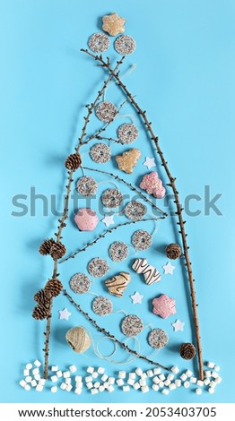 Eco- Alternative for Traditional Christmas Tree made of dry twigs, gingerbread cookies and marshmallows. Flat lay, blue background
