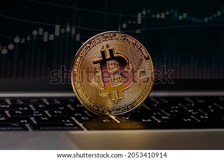 The concept of the bitcoin cryptocurrency financial market, trading. Bitcoin cryptocurrency is the future. The bitcoin logo on the laptop keyboard with a graph. Golden bitcoin - macro