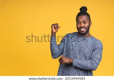 Portrait of happy young good-looking afro american man with in casual smiling, pointing aside with finger, with excited face expression isolated over yellow background.