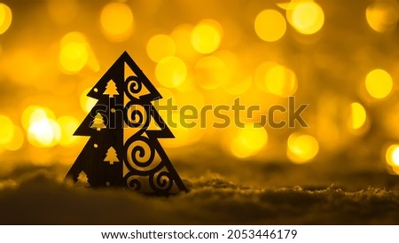 Hand-made silhouette of a Christmas wooden tree on a background of bright orange bokeh.