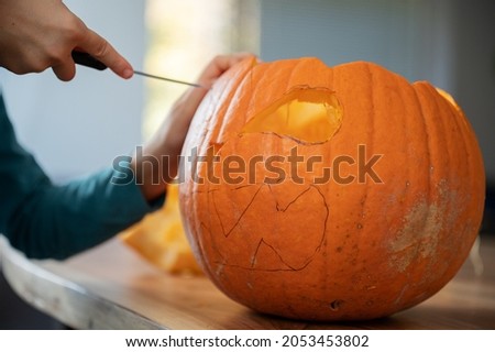 Closeup view of a child carving halloween pumpkin on a wooden table.