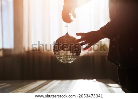 child hand holds disco ball at home