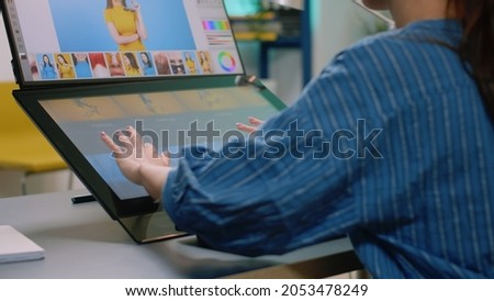 Close up of photographer hands using touch screen monitor to retouch photos at studio. Woman working as media editor retouching pictures with editing app on computer for image production
