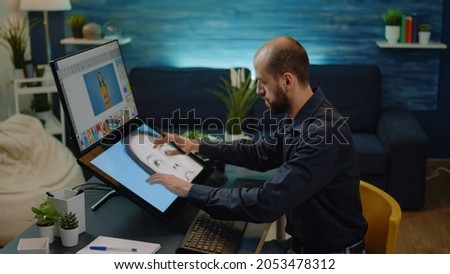 Male photographer doing editing work on touch screen monitor at studio. Photography editor working on retouching software and graphic tablet with stylus for professional pictures