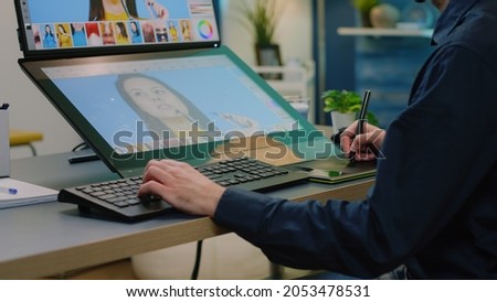 Close up of photographer hands using retouching software on touch screen computer. Photography artist with graphic tablet and stylus editing pictures with professional equipment.