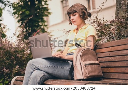 Photo of serious charming focused young woman hold hands computer sit bench outside outdoors city town