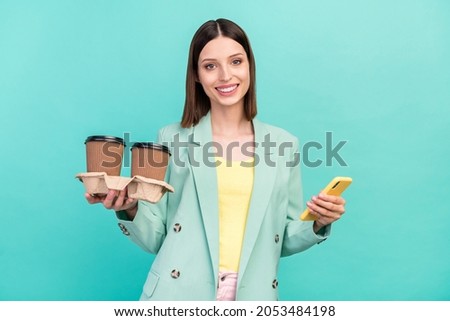 Photo of optimistic millennial brunette lady hold coffee telephone wear jacket isolated on cyan color background