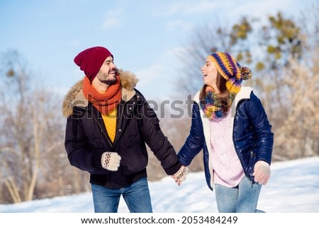 Photo of cheerful young couple happy positive smile walk outside hold hands together winter snow vacation laugh