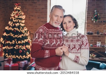 Photo portrait senior couple holding hands wearing red festive sweaters at home on new year