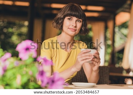 Photo of cute adorable young woman wear yellow t-shirt smiling drinking americano sitting cafe outside city street