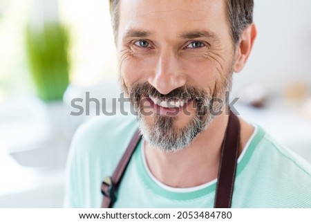 Photo of dreamy charming age man dressed blue t-shirt apron smiling indoors home room