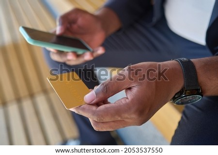 Close up picture of a man holding a credit card and a smartphone