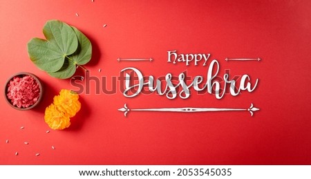 Happy Dussehra. Yellow flowers, green leaf and rice on red background. Dussehra Indian Festival concept. Royalty-Free Stock Photo #2053545035