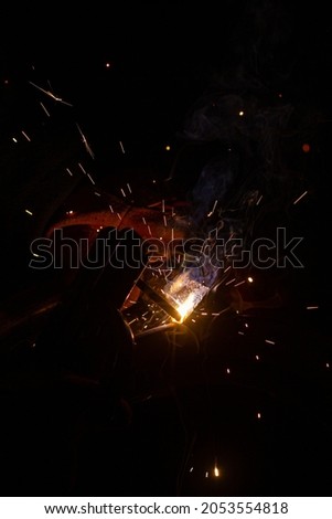 Close-up of a welder working in a workshop. Shallow depth of field. Welding of metal structures. Semi-automatic manual welding. MIG welding. 