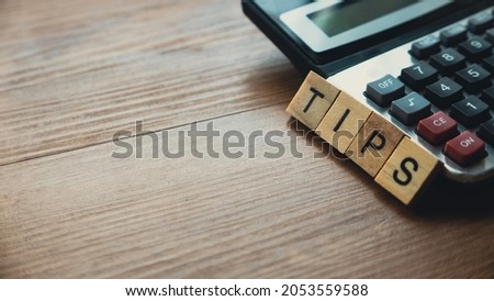 Selective focus of calculator and wooden alphabet of word Tips.