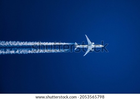 Sharp telephoto close-up of jet plane aircraft with contrails cruising from Tokyo to Chicago, altitude AGL 35,000 feet, ground speed 533 knots. Royalty-Free Stock Photo #2053565798