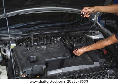 Auto mechanic checking CVT transmission fluid level on the oil dipstick. Royalty-Free Stock Photo #2053578533