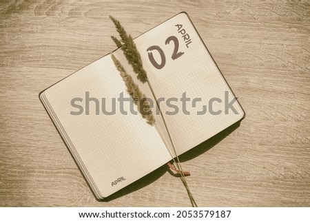 April 2. 2th day of month, calendar date. Blank pages of notebook are beige, with dried spikelets. Concept of day of year, time planner, spring month