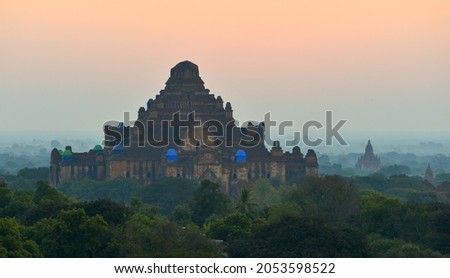 Beautiful sunrise scene in Bagan (Myanmar) with a complex of ancient brick temples shrouded in fog.