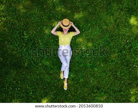 overhead view of woman laying down on green grass summertime Royalty-Free Stock Photo #2053600850