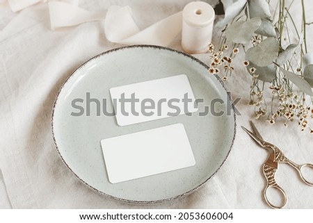 Blank paper sheet cards mockup on minimal table place setting top view on beige linen tablecloth.  Space for text. Tableware template, wedding invitation, menu. Scandinavian style.