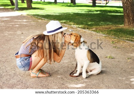 Cute girl kissing her beagle dog in nature outdoors. Lovely shot
