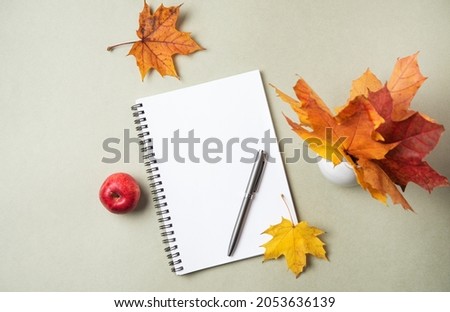 Concept autumn flat lay with yellow maple leaves,  notebook, pen and apple  on a pastel green background. Top view   and copy space. 