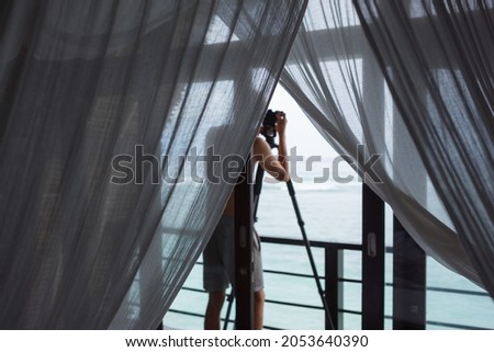 Anonymous camera man on balcony filming sea waves